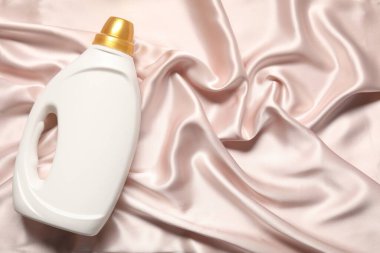 Bej kumaşlı bir şişe yumuşatıcı, üst manzara. Metin için boşluk