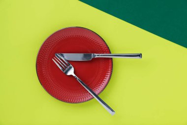 Yeşil arka planda tabak ve çatal bıçak takımı, üst görünüm