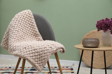 Yünlü battaniye ve dekorlu rahat bir koltuk.