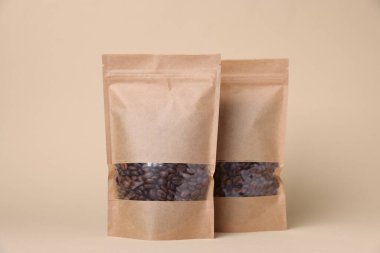 Bej arkaplanda kahve çekirdekleri olan fermuarlı stand-up torbaları. Tasarım için model