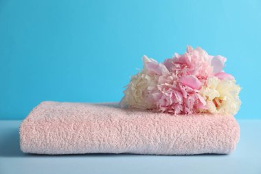 Açık mavi arkaplanda yumuşak havlu ve şakayık çiçekleri, yakın plan.