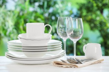 Bulanık yeşil arka planda beyaz masada farklı temiz tabaklar