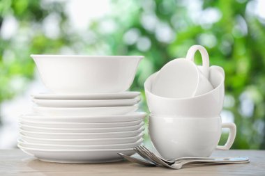 Ahşap masada, bulanık yeşil arka planda farklı temiz tabaklar.