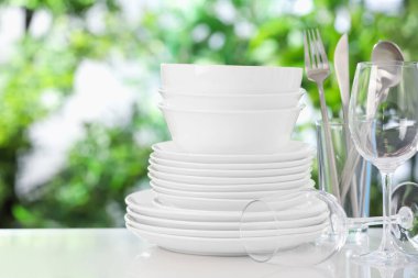 Bulanık yeşil arka planda beyaz masada farklı temiz tabaklar