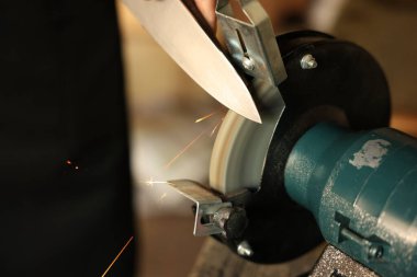 Bıçak keskinleştiren bir adam, kapalı mekanda, yakın plan. Metin için boşluk