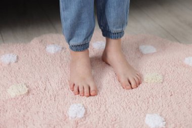 Evdeki yumuşak halıdaki kız, yakın plan.