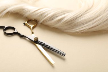Bej arkaplanda saç tokası ve makas, yakın plan.