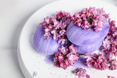 Sabun çubukları, deniz tuzu ve leylak çiçekleri beyaz masada, yakın plan.