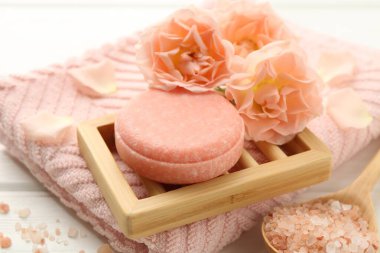 Sabun çubuğu, deniz tuzu ve beyaz ahşap masada güzel çiçekler, yakın plan.