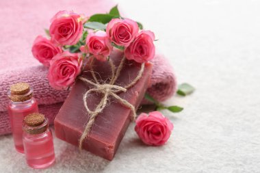 Sabun barları, havlular, esaslı yağlar ve bej masadaki güzel güller, yakın plan. Metin için boşluk
