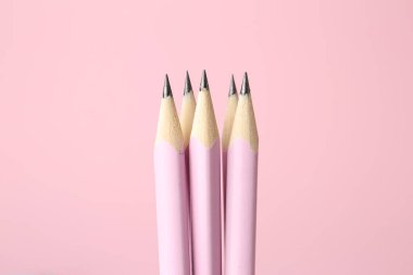 Many graphite pencils on pink background, closeup