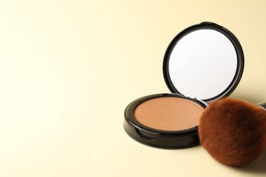 Aynalı açık yüz pudrası ve bej arka planda fırça, yakın plan. Metin için boşluk