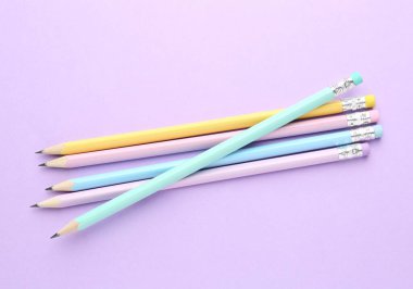 Menekşe arkaplanda silgileri olan birçok grafit kalem, düz konum