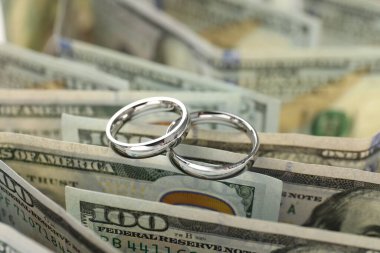 Gümüş alyanslar ve dolar banknotları, yakın plan.