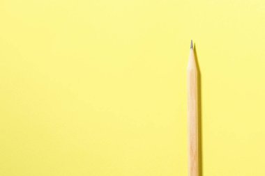 Sarı arka planda bir grafit kalem, en üstte. Metin için boşluk