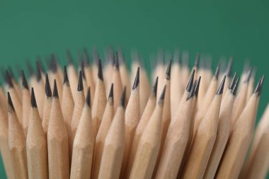 Yeşil arkaplanda birçok grafit kalem, yakın plan