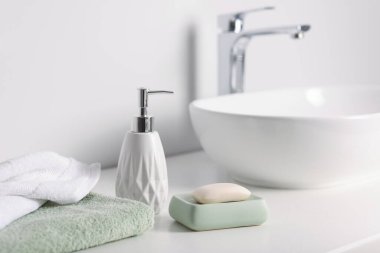 Sabun çubuğu, bir şişe kozmetik ürün ve kapalı alandaki beyaz tezgahta havlular, yakın plan.