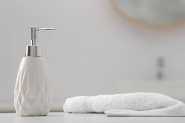 Şişede sıvı sabun ve beyaz masa içinde havlu.