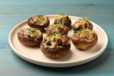 Eritilmiş peynirli lezzetli mantarlar ve açık mavi ahşap masada kekik, yakın plan.