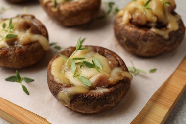 Eritilmiş peynirli lezzetli mantarlar ve gri masadaki kekik, yakın plan.