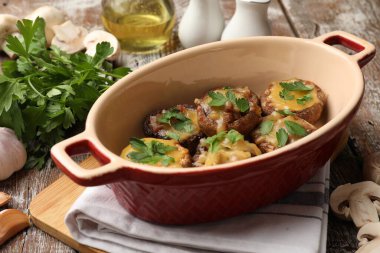 Eritilmiş peynirli ve maydanozlu lezzetli mantarlar ahşap masa üzerinde, yakın plan.