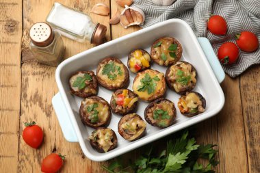 Ahşap masaya konmuş, ahşap tabakta ve malzemelerde lezzetli mantarlar var.