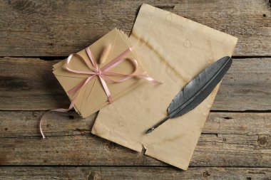 Aşk mektupları, tüy kalem ve parşömen kâğıtları ahşap masanın üstünde.