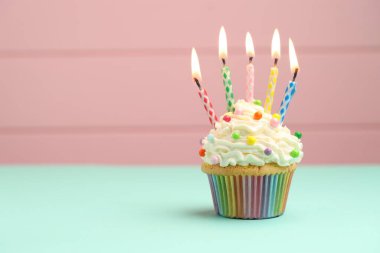 Turkuaz masadaki kekin içinde mumları pembe arkaplanla yakmak, metin için boşluk