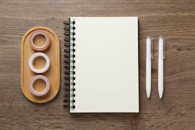 Not defteri, dekoratif el sanatları kasetleri ve tahta masa üzerindeki kalemler, düz yatış.