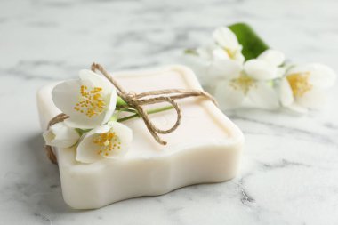 Sabun çubuğu ve yasemin çiçekleri beyaz mermer masada, yakın plan.