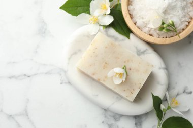 Sabun çubuğu, deniz tuzu ve yasemin çiçekleri beyaz mermer masada, düz yerde. Metin için boşluk