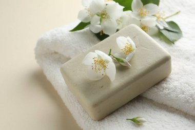 Bej arka planda sabun, havlu ve yasemin çiçekleri, yakın plan.