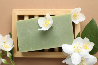 Açık kahverengi arka planda sabun ve yasemin çiçekleri, düz uzanmış