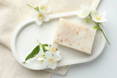 Sabun çubuğu ve yasemin çiçekleri beyaz masada, düz yatıyordu.