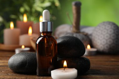 Dökücü, taşlar ve yanan mumla kaplıca bileşimi ahşap masada bulanık yeşil arka planda, yakın plan