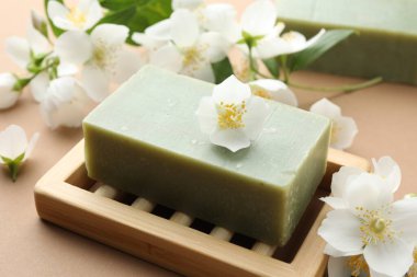 Açık kahverengi arka planda sabun ve yasemin çiçekleri, yakın plan.