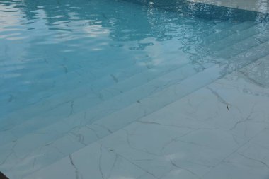 Açık yüzme havuzunda dalgalı ve merdivenli temiz su, yakın çekim.