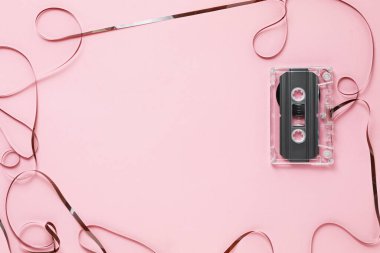 Pembe arka plandaki ses kasetindeki manyetik banttan yapılmış çerçeve, üst görünüm. Metin için boşluk