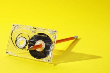 Sarı arka planda kurşun kalemle ses kaseti geri sarılıyor. Yakın plan. Metin için boşluk