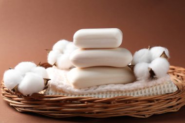 Kahverengi arka planda hasır sepetin içinde beyaz sabun ve pamuk yığını, yakın plan