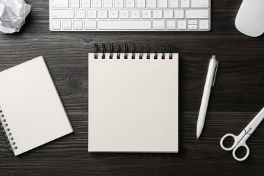 Defterler, diğer kırtasiye malzemeleri, bilgisayar klavyesi ve fare siyah ahşap masa üzerinde, düz yatıyordu.