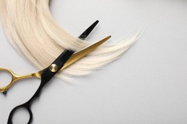 Sarı saç tokası ve makas açık gri arka plan, üst manzara. Metin için boşluk