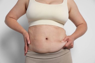 Hafif arka planda aşırı göbek yağı olan kadın, yakın plan. Aşırı kilolu