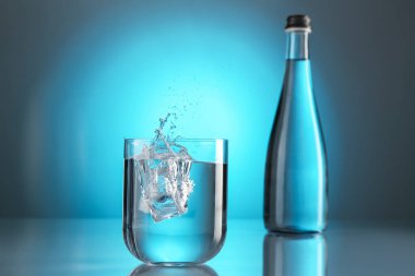 Ayna masasının üzerindeki camdan akan tatlı su, açık mavi gradyan plana karşı. Arka ışıklandırma