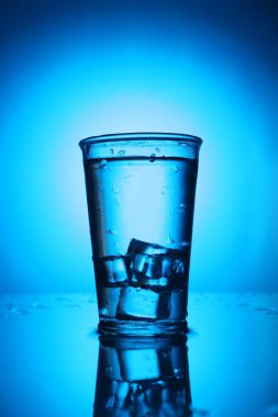 Ayna masasının üzerinde buzlu taze su mavi gradyan arka planda. Arka ışıklandırma