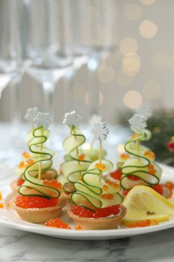 Arka planı bulanık ışıklarla kaplı beyaz mermer masa üzerinde lezzetli kanepeler, yakın plan. Bokeh etkisi