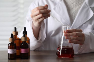 Laboratuardaki ahşap masada lüks parfüm üreten profesyonel parfümcü.