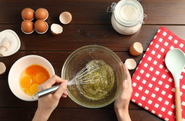 Ahşap masada yumurta beyazı çırpan bir kadın.