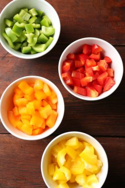 Taze renkli dolmalık biberler ahşap masadaki kaselerde, düz yatıyordu.