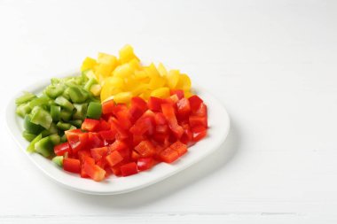 Beyaz ahşap masada taze dolmalık biber parçaları, yakın plan. Metin için boşluk